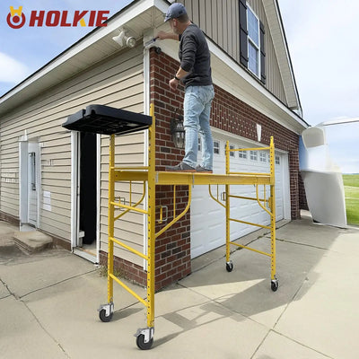 Outdoor house renovation, worker on yellow mobile scaffolding fitted with HOLKIE 5‑inch dual‑brake scaffold casters, 1‑1/4" square stem